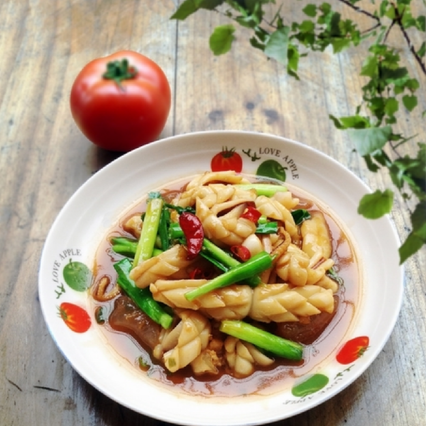 韭菜炒鱿鱼成品图,蒸汽袅袅上升,画面温馨诱人,适合用于美食推广 一盘热腾腾的韭菜炒鱿鱼盛在蓝色陶瓷盘中,菜肴色泽鲜明,鱿鱼卷曲,韭菜碧绿