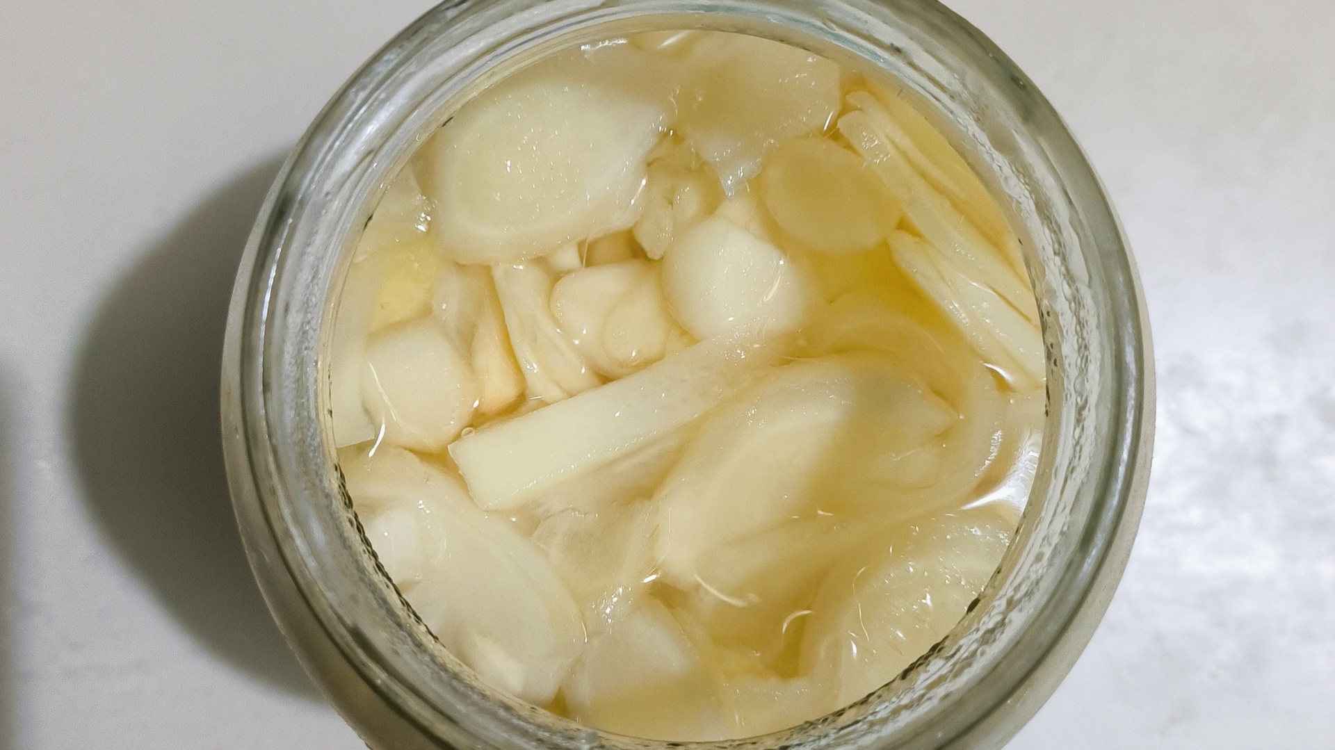 老姜泡姜成品美食摆盘图：琥珀色姜片堆叠成小山，点缀红椒丝、香菜叶、白芝麻，背景为青花瓷盘与竹筷