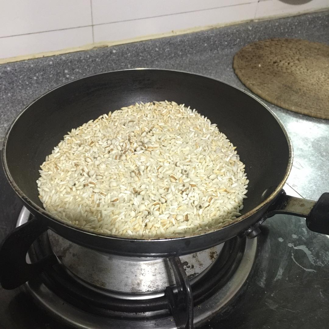 一个不粘平底锅置于燃气灶上,锅中两个金黄色的圆形红薯糯米饼正在干烙,表面微微鼓起并出现浅褐色斑点,旁边摆放着木铲和未加工的面团球,背景为现代简约厨房环境 红薯糯米饼烙制过程