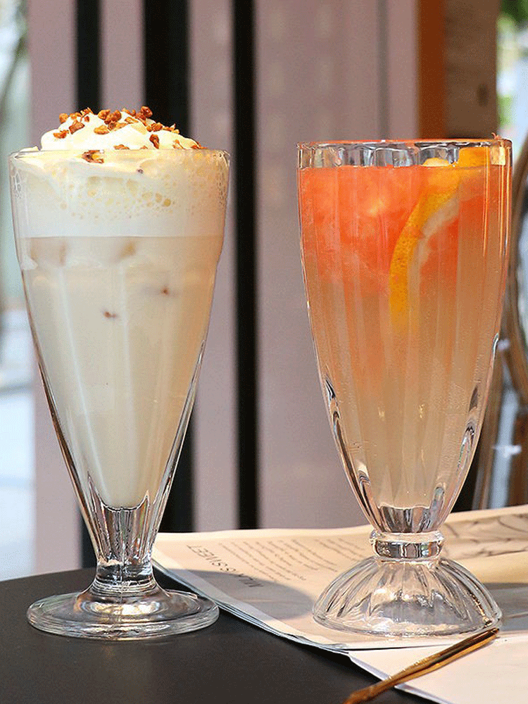 三只不同颜色的玻璃杯排列在木纹桌面上,分别盛放粉紫色火龙果酸奶汁、黄绿色猕猴桃混合果汁、乳白色香蕉奶昔,每杯插有纸质小旗标注名称,背景为绿植与阳光光影 火龙果酸奶组合创意饮品拼盘