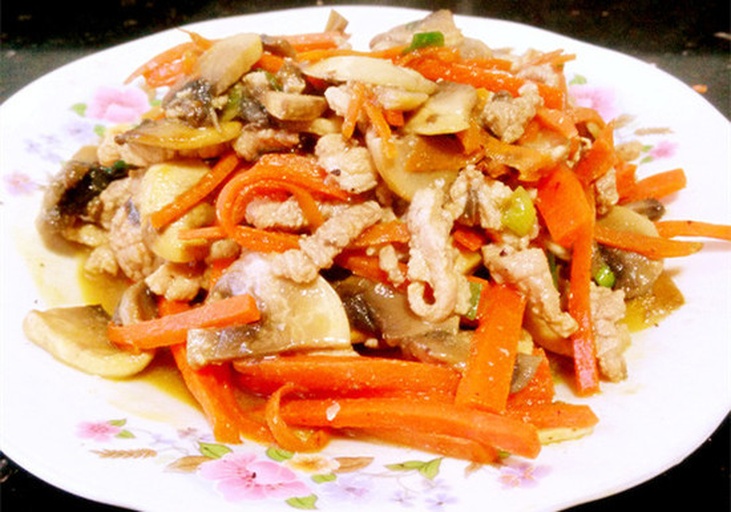 成品菜肴特写：胡萝卜与蘑菇混合炒制，颜色鲜明，橙红与乳白交织，盛于白色瓷盘中，点缀绿色葱花