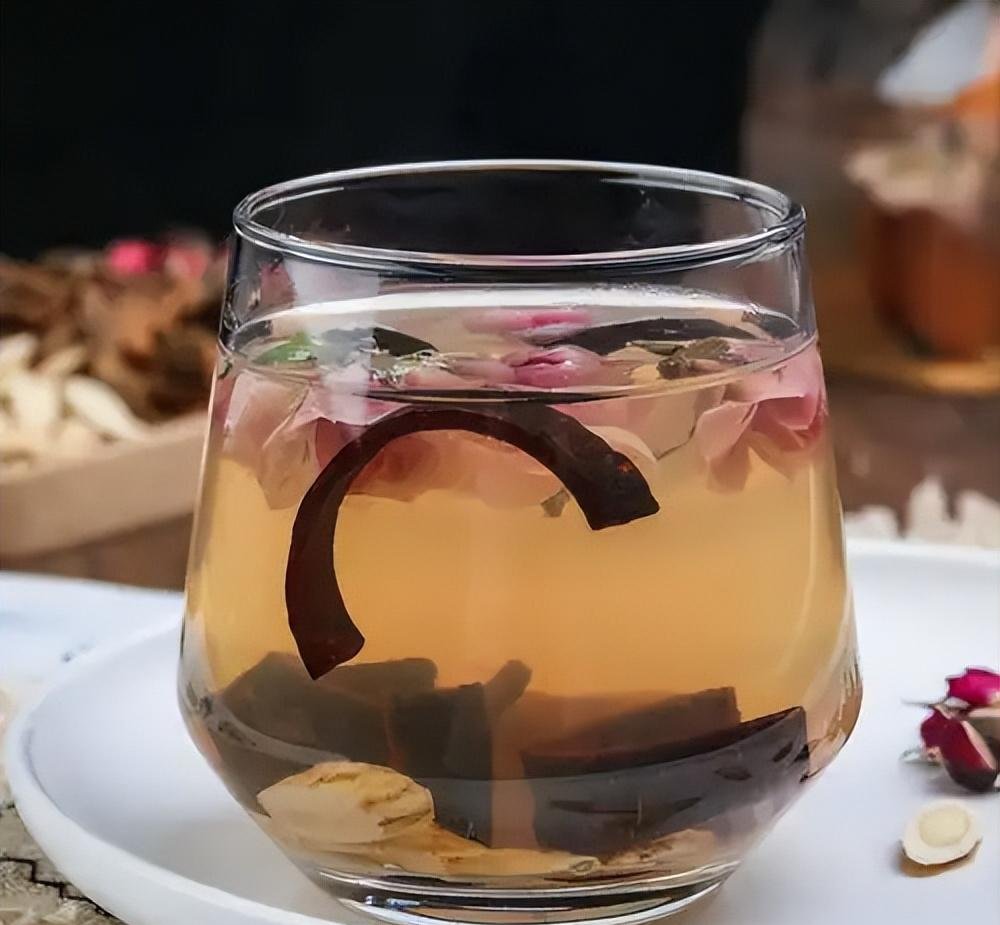 成品茶汤特写:300mL淡琥珀色澄清茶汤置于白瓷品茗杯中,杯底沉淀少量葛根细粉,水面漂浮2片舒展的玫瑰花瓣,茶汤表面有极薄油脂膜(源自玫瑰花挥发油),室温25℃下静置30分钟无浑浊 葛根玫瑰茶饮成品效果展示