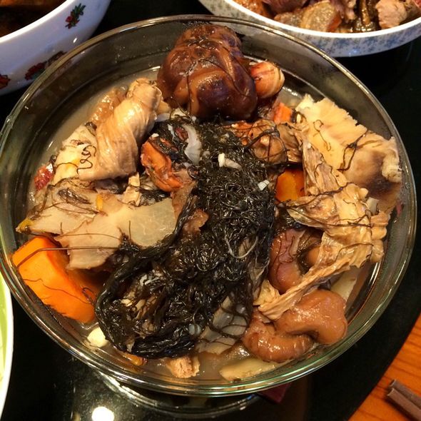 一碗热气腾腾的炖菜,深褐色的厚海带与红亮的牛肉块交织在一起,汤汁浓稠,表面浮着少许香菜和葱花,背景为木质餐桌,营造出温暖的家庭用餐氛围 厚海带炖牛肉特写