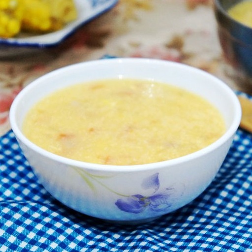 一大碗刚制作完成的金白色甜玉米花盛放在陶瓷碗中,表面微微泛着黄油光泽,旁边点缀着小块黄油和糖罐,背景虚化的木质餐桌营造温馨居家氛围 成品甜玉米花摆盘展示