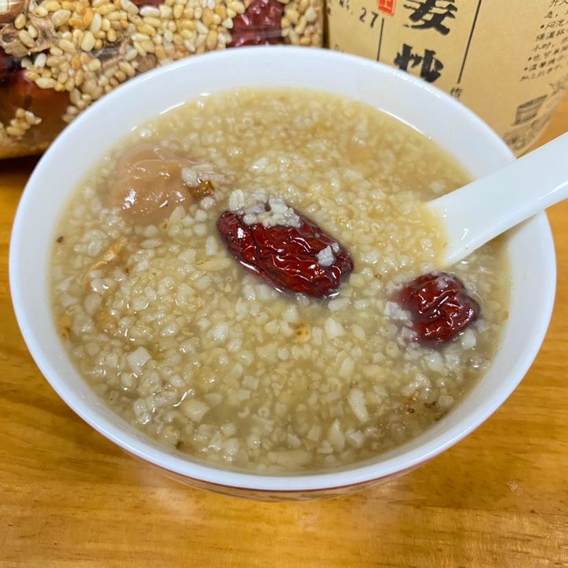 一碗热腾腾的红薯红枣粥特写,粥体浓稠,可见明显的红薯块与去核红枣颗粒,表面有轻微油光,旁边配有木勺和绿叶点缀,体现家常养生风格 红薯红枣粥成品图