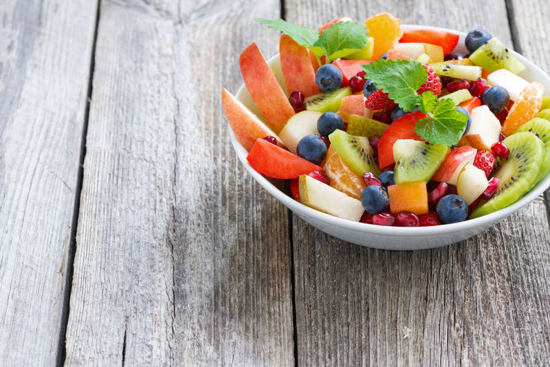 厨房台面上摆放着一碗由切块早酥梨、蓝莓、核桃仁组成的水果沙拉,旁边有一瓶蜂蜜和一杯刚榨好的梨汁,背景为自然光线下的窗台,整体呈现健康生活氛围 早酥梨家庭食用场景图