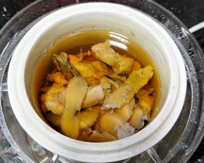 厨房场景中,厨师正在将切碎的小黄姜加入炖汤锅中,蒸汽升腾,旁边摆放着新鲜小黄姜和调料碗,体现其日常饮食应用 小黄姜烹饪应用场景