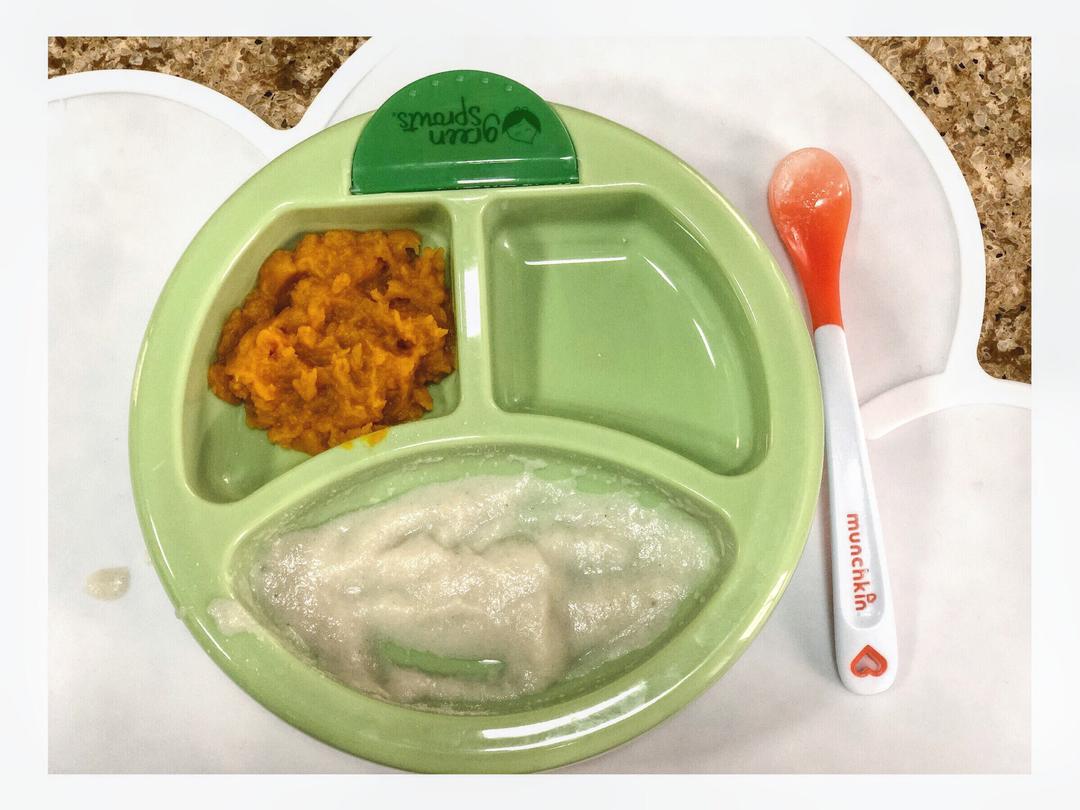 白色陶瓷碗中盛有细腻的橙色胡萝卜泥,旁边配有小勺和围兜,背景为温馨的家庭厨房环境,强调婴幼儿营养辅食的应用场景 胡萝卜泥辅食与婴儿餐具组合图
