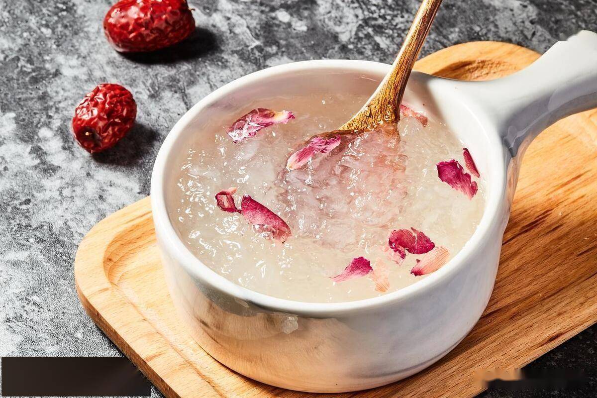 一碗晶莹剔透的湘莲燕窝,燕丝分明缠绕在洁白莲子间,表面点缀红色枸杞与金黄桂花,盛于青瓷小盅内,背景虚化竹制托盘,整体呈现高级中式美学风格 成品湘莲燕窝特写图