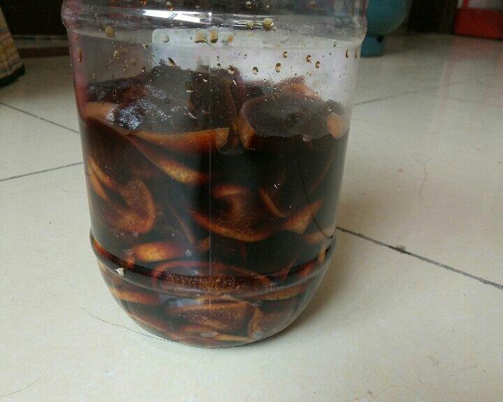 一个透明玻璃广口瓶内盛满乳白色腌汁,里面浸泡着整齐排列的白色沙梨片,液体清澈见底,瓶口用橡胶塞密封,放置在木架阴影下的阴凉角落 玻璃罐中正在腌制的沙梨酸