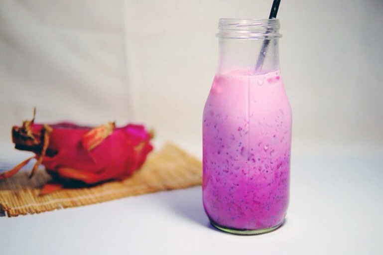 火龙果山药奶昔分层效果图：渐变玫红奶昔盛于透明玻璃杯中，底部浓稠、中段悬浮火龙果籽、顶部浮着白色奇亚籽凝胶与肉桂粉纹路，杯壁无挂壁残留