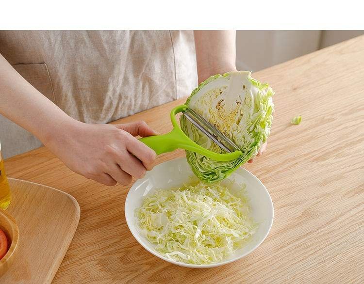 一位家庭主妇正在厨房砧板上用刀将圆包菜切成细丝,旁边配有不锈钢碗和调料瓶,操作台整洁明亮,体现日常健康饮食场景 家庭厨房中正在切丝的圆包菜