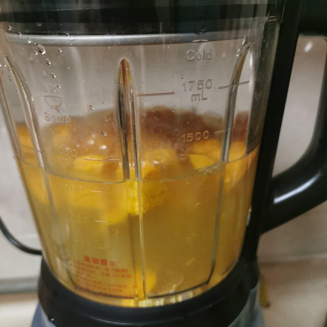 搅拌机中正在制作橙子香蕉燕麦奶昔，杯壁可见细腻泡沫