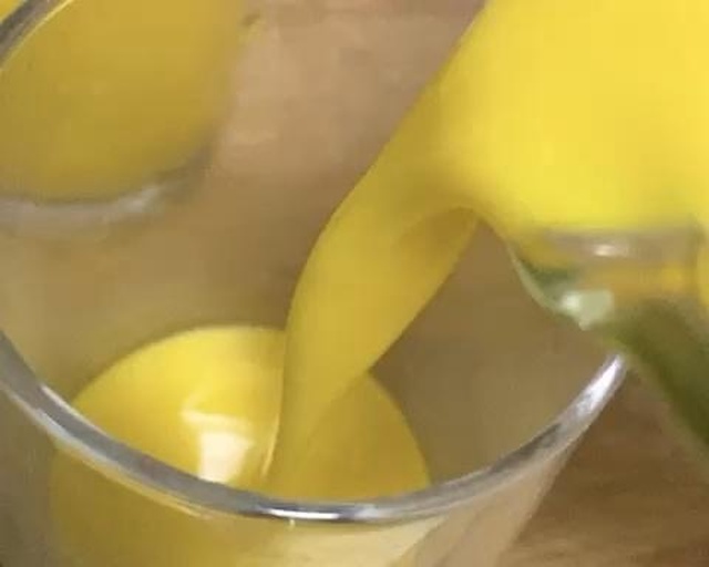 一杯翠绿色的果蔬汁被缓缓倒入透明玻璃杯中,液体流动清晰可见,杯身凝结水珠,旁边放着黄瓜片和奇亚籽作为装饰,背景虚化 绿色果蔬汁倒入玻璃杯特写
