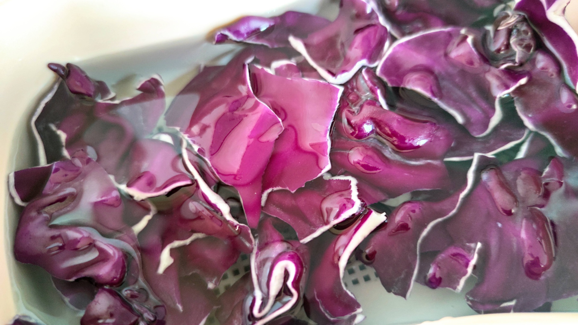 紫甘蓝切片浸泡在透明液体中，液体呈现淡紫色，旁边放置一瓶白醋