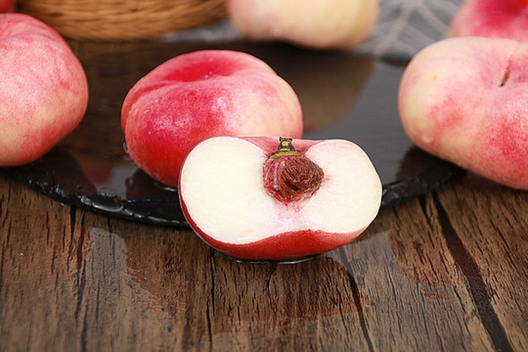 展示一个切开的蟠桃,露出果核和果肉结构 蟠桃切开图