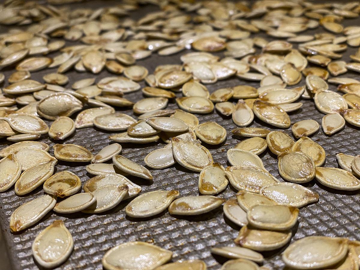 甜瓜籽在烤盘上烘焙的过程,展示其制作健康零食的步骤 甜瓜籽烘焙过程图
