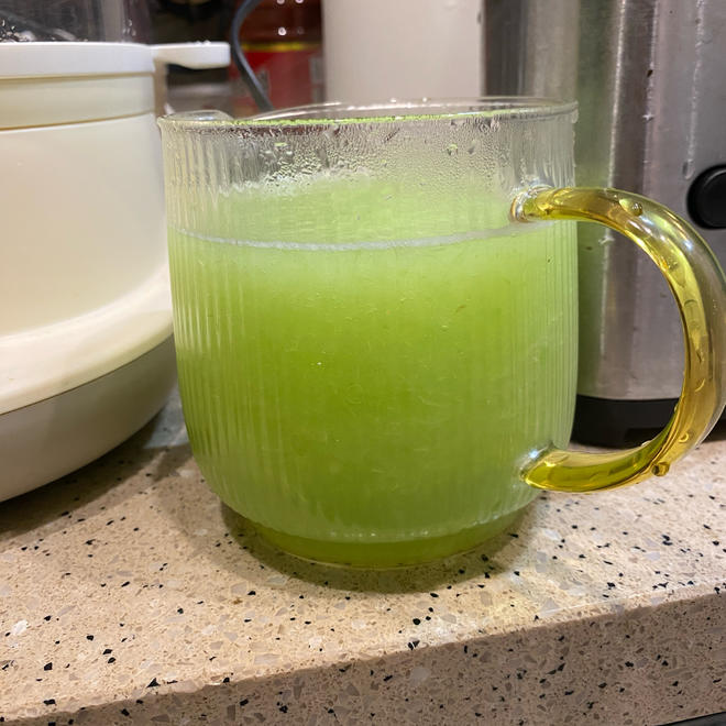 一名小学生戴着护目镜和手套,在厨房桌面上操作多个玻璃杯,杯中液体呈现红、紫、蓝、绿色,背景有紫甘蓝叶片和标签纸,显示‘酸’‘中’‘碱’字样 儿童在家长指导下进行紫甘蓝酸碱实验