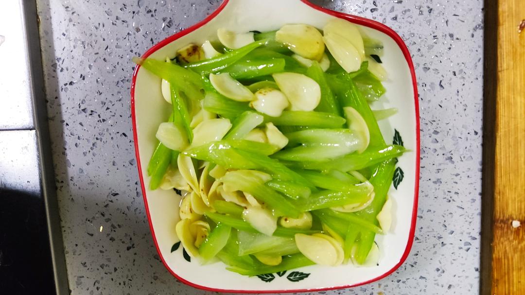 一盘刚出锅的蒜蓉芹菜炒圆椒,盛放在白色瓷盘中,菜肴颜色鲜明:翠绿的芹菜段与亮绿色的圆椒条交错分布,表面略带油光,可见蒜末点缀,展现家常炒菜的真实质感 芹菜炒圆椒成品菜肴特写