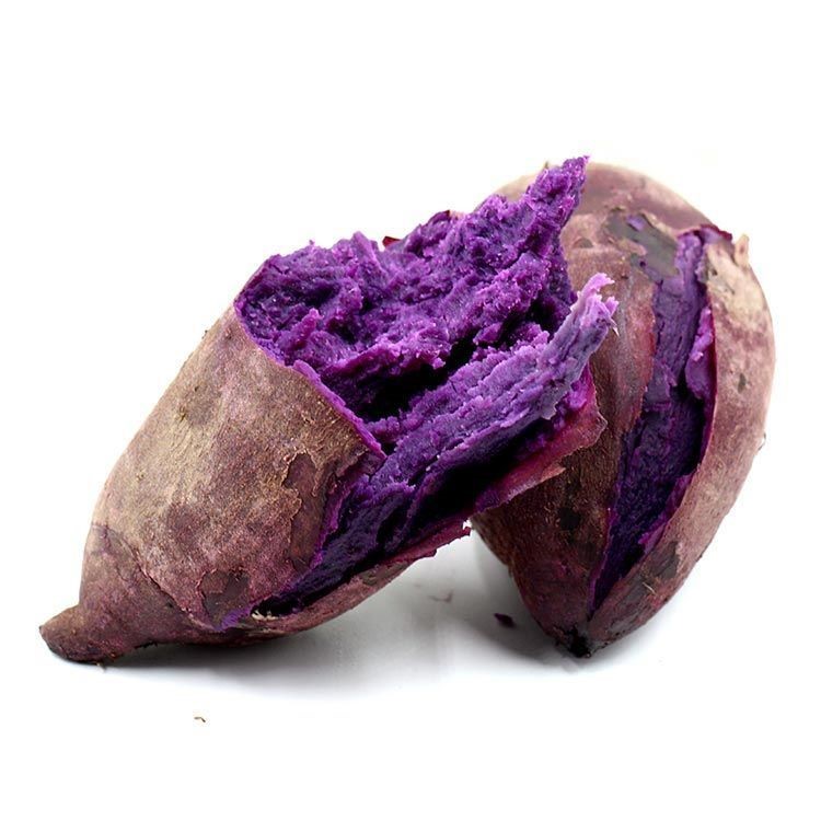 一个新鲜紫薯被横向切开,露出深紫色的内部肉质,颜色均匀饱满,表皮呈浅褐色,切面湿润有光泽,背景为木质砧板,周围散落少量紫薯碎屑 紫薯切面特写