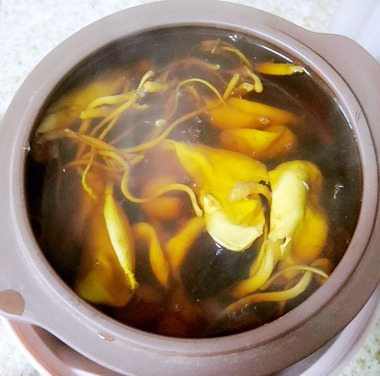 红皮白心萝卜煮水制作过程：不锈钢锅中清水微沸，红白分明的萝卜薄片悬浮其中，蒸汽升腾，滤布过滤后琥珀色清亮汤汁缓缓流入玻璃量杯
