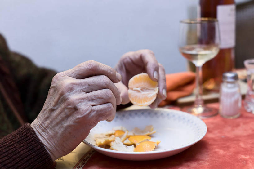 一家人在客厅围坐,孩子开心地剥着蜜橘,桌上摆放着装满蜜橘的竹篮和茶杯,窗外可见橘园一角,营造温馨家庭氛围 家庭享用蜜橘场景