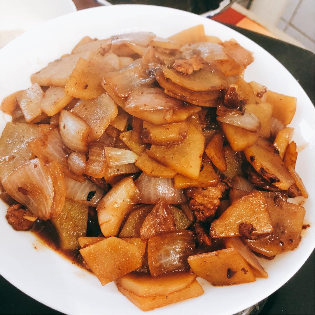 高清摆拍:成品洋葱炒土豆盛于素雅白瓷盘,土豆片片分明、光泽润亮,洋葱丝卷曲金黄,葱花碧绿、芝麻乌黑,整体呈现‘干香、亮泽、层次分明’的优质家常菜视觉标准,突出健康质朴的餐桌美学 成品装盘特写:浅口白瓷盘中盛放金黄微焦的洋葱丝与柔韧半透明土豆片,点缀翠绿葱花与黑芝麻,背景为木质餐桌与玻璃调料瓶