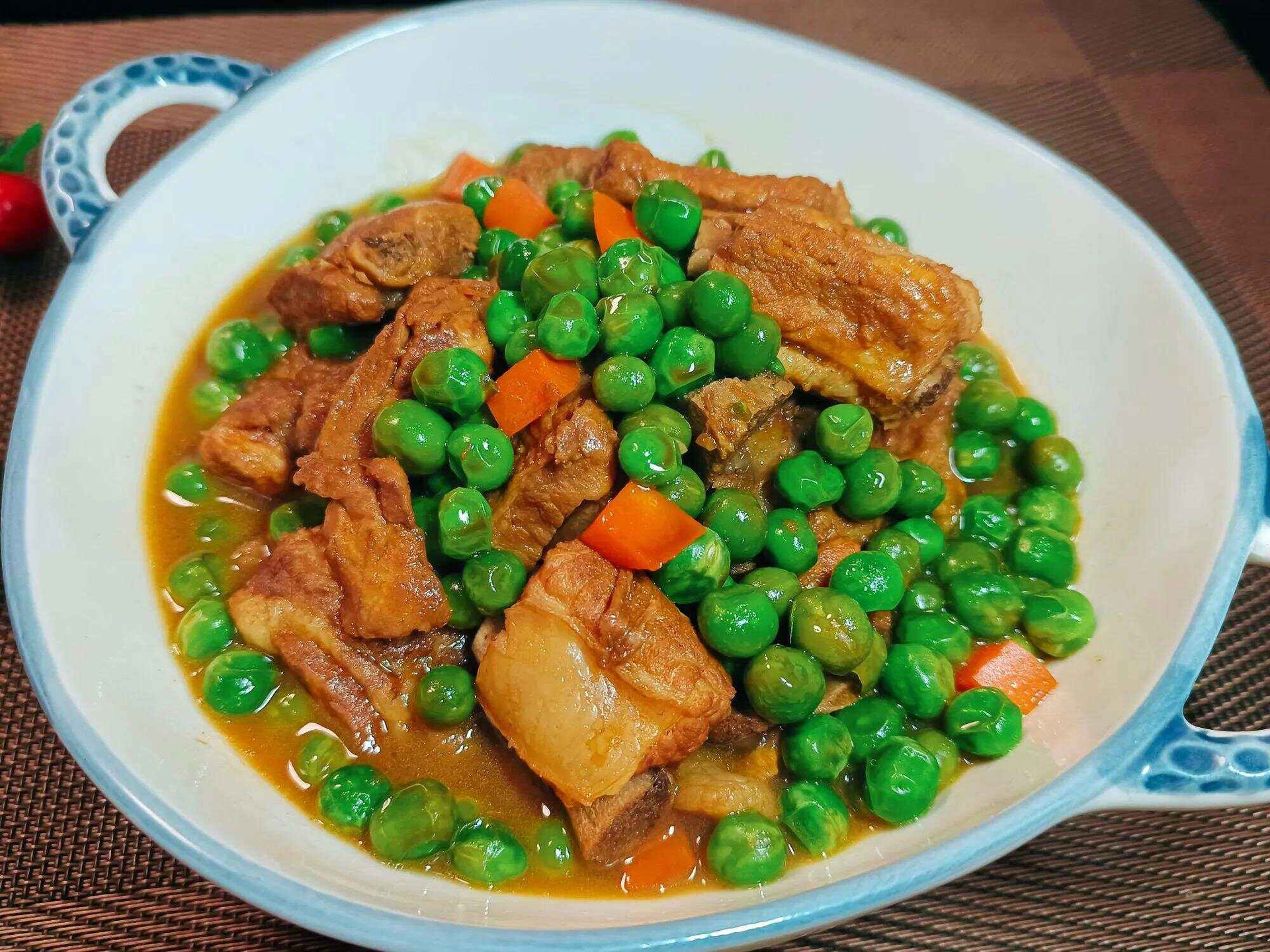 青豌豆炖排骨正在炖煮中，锅中汤汁浓郁，青豌豆与排骨交融