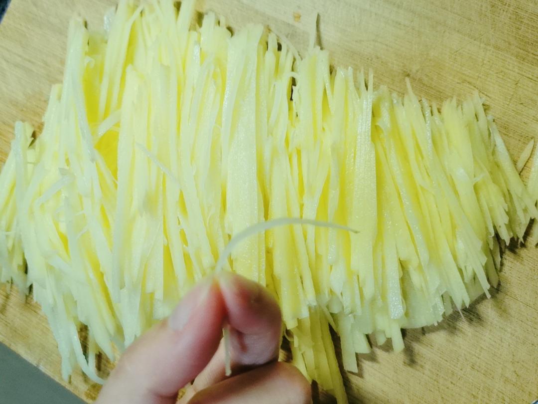 一位厨师正在砧板上将去皮后的白色土豆切成均匀细丝,光线明亮,背景干净整洁,突出食材新鲜与刀工精细 土豆切丝过程特写