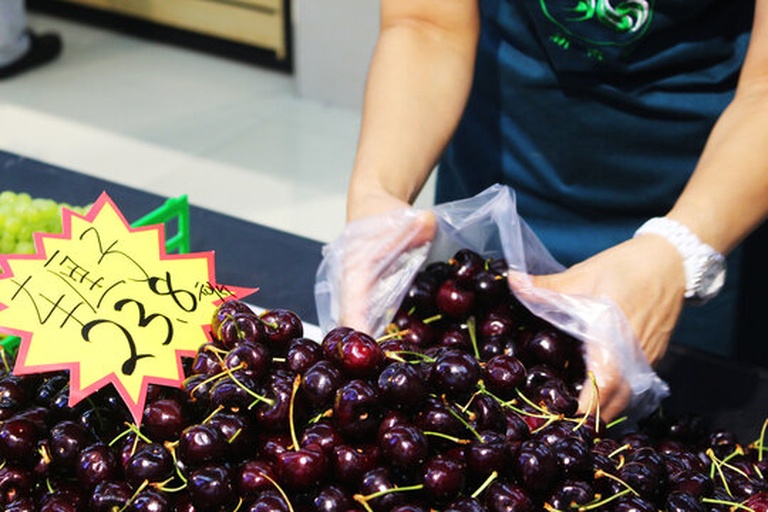 一名消费者正在仔细查看车厘子包装上的标签和溯源信息，旁边放着手机扫描二维码