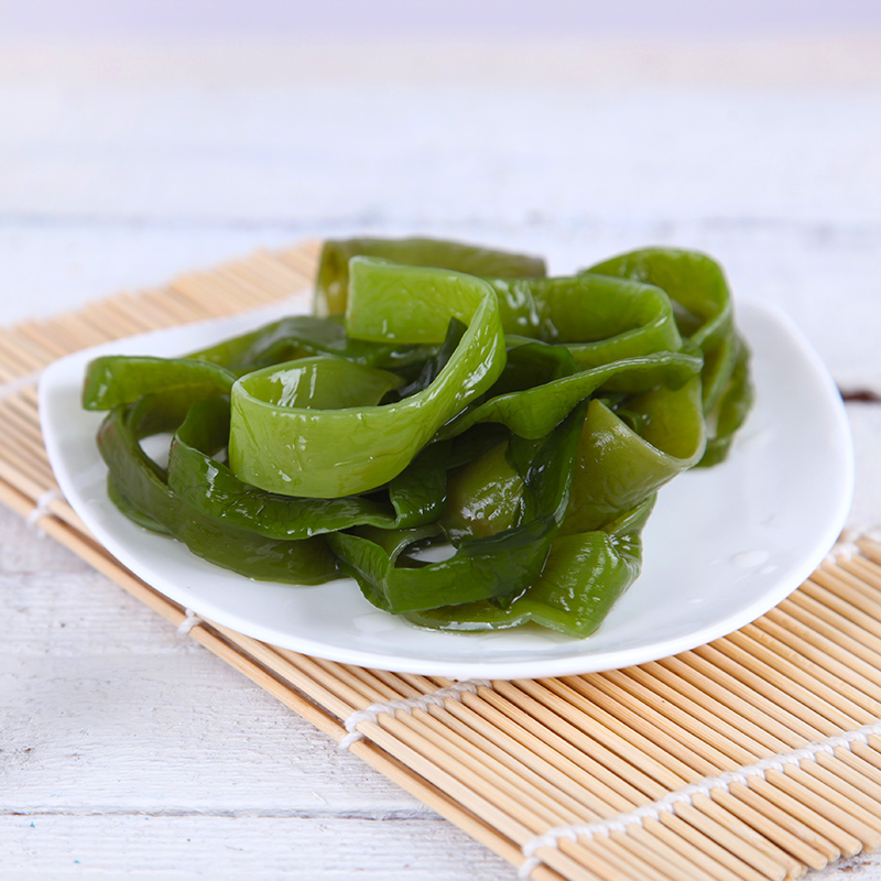 家庭餐桌上一盘清蒸带鱼搭配绿叶蔬菜和糙米饭