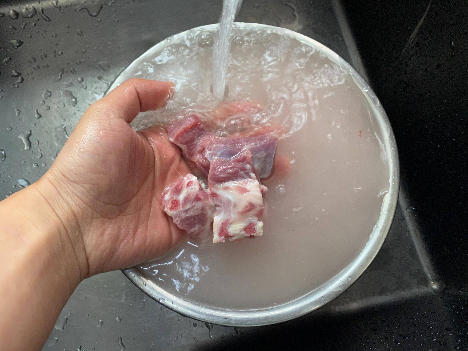 一位厨师正在厨房中清洗一只整鸡,水龙头下水流清澈,鸡肉表面干净光亮,背景有砧板和刀具,展现食材准备阶段的真实场景 图片描述