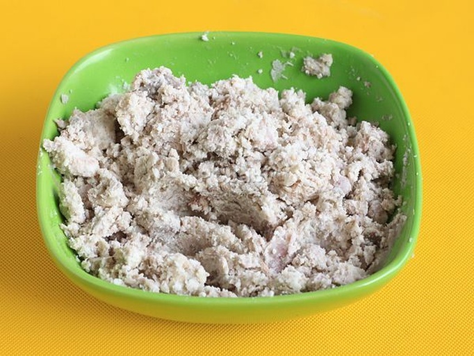 白色瓷碗盛装浅黄色粥品,表面漂浮着细碎的绿色芹菜末和少量鸡肉纤维,背景为木质餐桌和筷子 一碗热腾腾的西芹鸡肉粥,米粒软烂,西芹呈淡绿色碎末状均匀分布在粥中