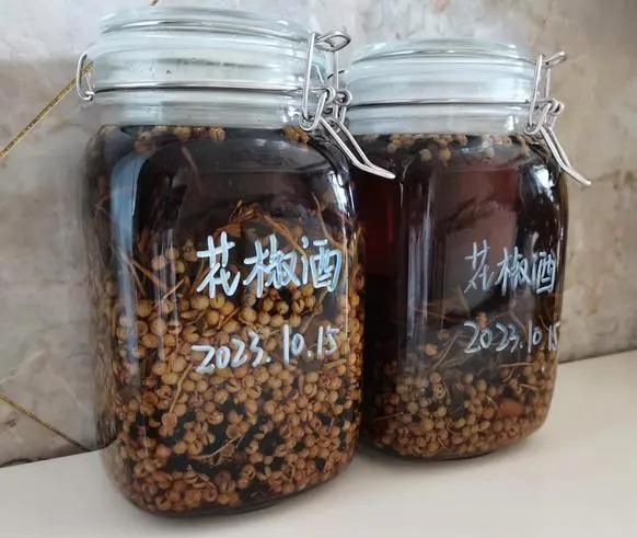 一个透明玻璃泡酒罐中浸泡着数段浅黄色的白胡椒根,酒体清澈微带金黄,罐旁放置一小碗冰糖和一支记号笔,标签纸上写着“白胡椒根酒 - 起始日期:2025.04.01”,整体摆放在木质茶几上,背景为书架与绿植 泡酒过程展示
