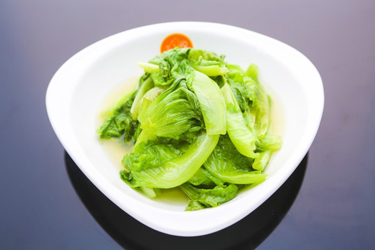 一张木质餐桌上并排放置一株散叶生菜和一颗西生菜,左侧散叶生菜叶片舒展呈扇形,颜色翠绿;右侧西生菜为紧凑球形,外叶深绿内芯乳白,旁边配有不锈钢刀具和砧板,展示准备切配的状态 厨房中两种生菜并列对比