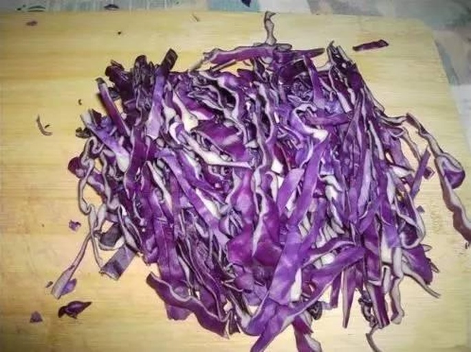 一张拼图展示紫甘蓝的不同烹饪形式:左侧为切丝后的凉拌菜,中间为烤箱烘烤的紫甘蓝片,右侧为与胡萝卜混合的沙拉,背景为木质餐桌和厨具 家庭厨房中紫甘蓝的多种料理方式拼图