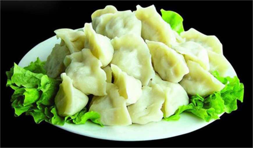 一盘刚出锅的蒸饺或水饺,呈半月形排列整齐,外皮晶莹透亮可见绿色菜粒,旁边配有酱油醋碟和红辣椒油,热气袅袅升起,背景为木质餐桌,营造温馨家常氛围 成品娃娃菜饺子摆盘