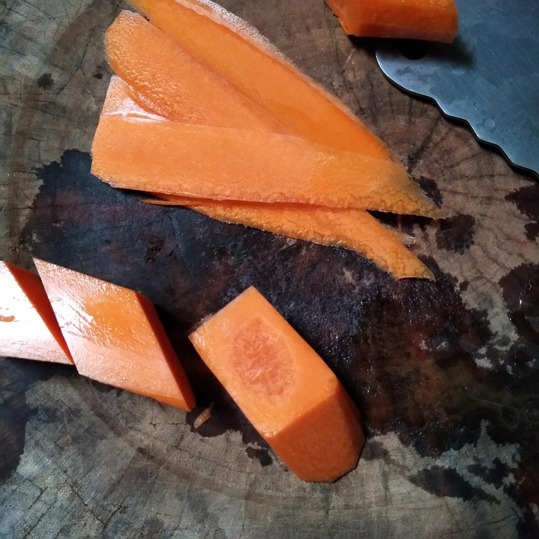木质砧板上摆放着刚切好的胡萝卜圆片和条状块,橙红色泽明亮,表面水润有光泽,旁边有一把不锈钢厨刀和一小撮香菜叶,背景模糊,突出食材的新鲜感 厨房中切好的新鲜胡萝卜片