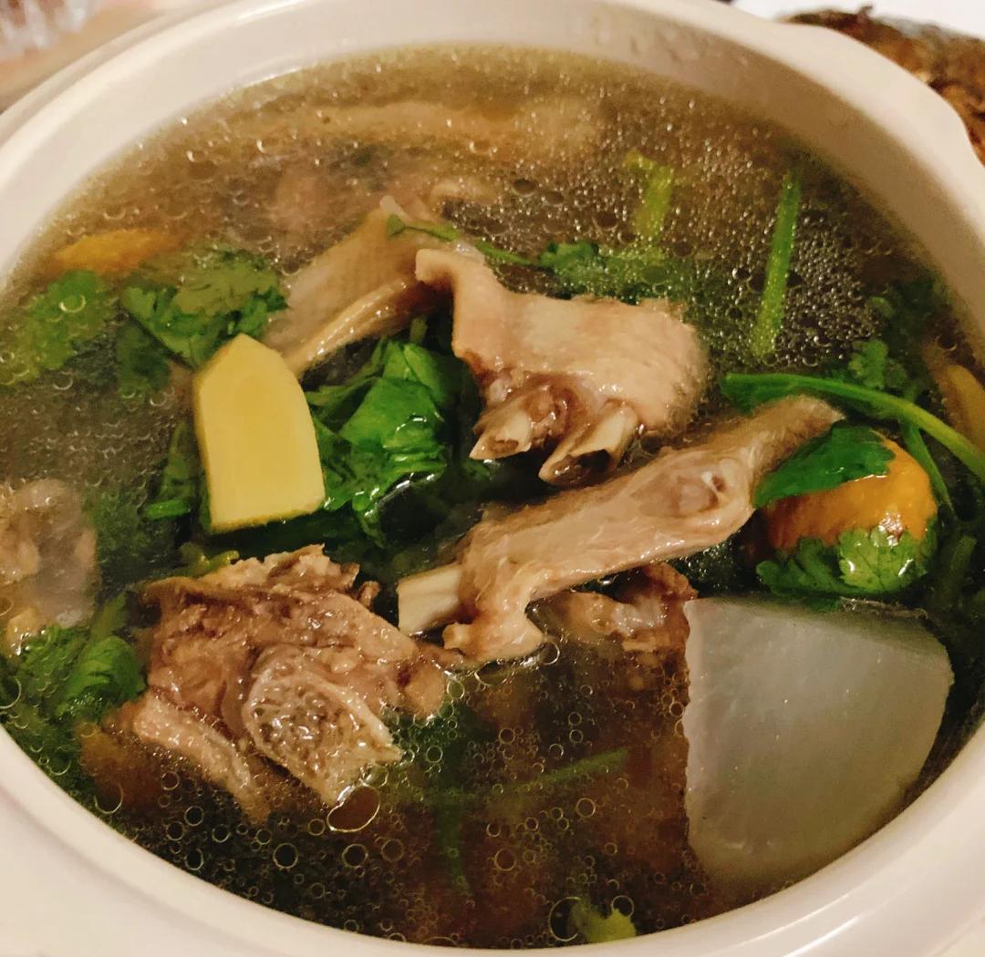 俯拍高清图:青花瓷汤碗中琥珀色清亮汤汁,沉浮着半透明鸭肉块与柔韧酸萝卜片,汤面浮少量金黄色鸭油星,碗沿搁置竹筷与小碟盛装新鲜香菜末,凸显‘清汤不浊、油星不腻、料形完整’三大工艺特征 老鸭子炖酸萝卜成品汤品特写