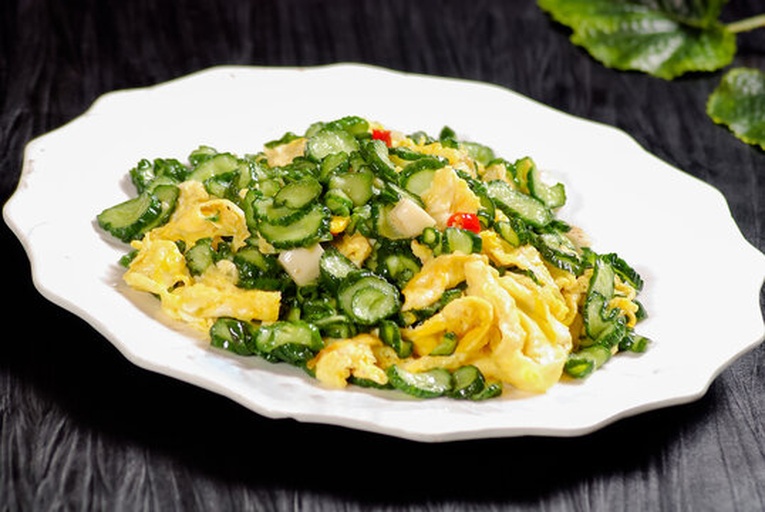 小黄瓜与新鲜鸡蛋摆放在木质砧板上，旁边有葱段和调料瓶，背景为厨房台面