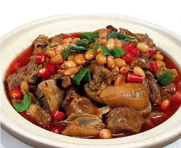 深色陶瓷碗中盛放着红亮油润的红烧肉炖花生,肉块饱满,花生完整嵌于汤汁中,表面泛着光泽,旁边配有白米饭和绿色青菜,整体构图温馨诱人 成品盛盘图