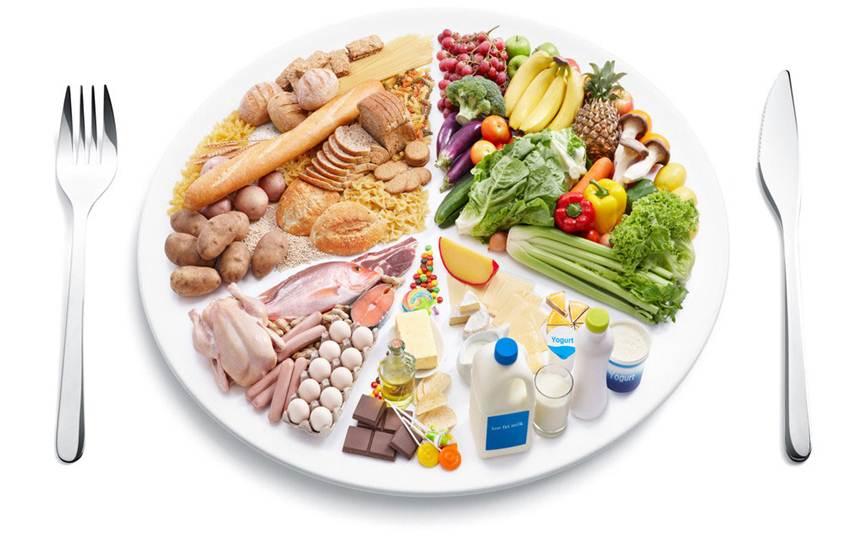一名专业营养师坐在办公桌前,手持平板电脑展示膳食结构图表,对面坐着一位咨询者,桌上摆放着食物模型,包括生菜、鸡蛋、糙米和坚果,背景墙上挂着《中国居民平衡膳食宝塔》 营养师在办公室为顾客做饮食指导