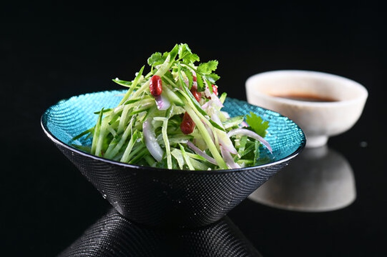 一盘由黄瓜片、西红柿块、紫甘蓝丝、鸡胸肉丁和坚果组成的彩色沙拉