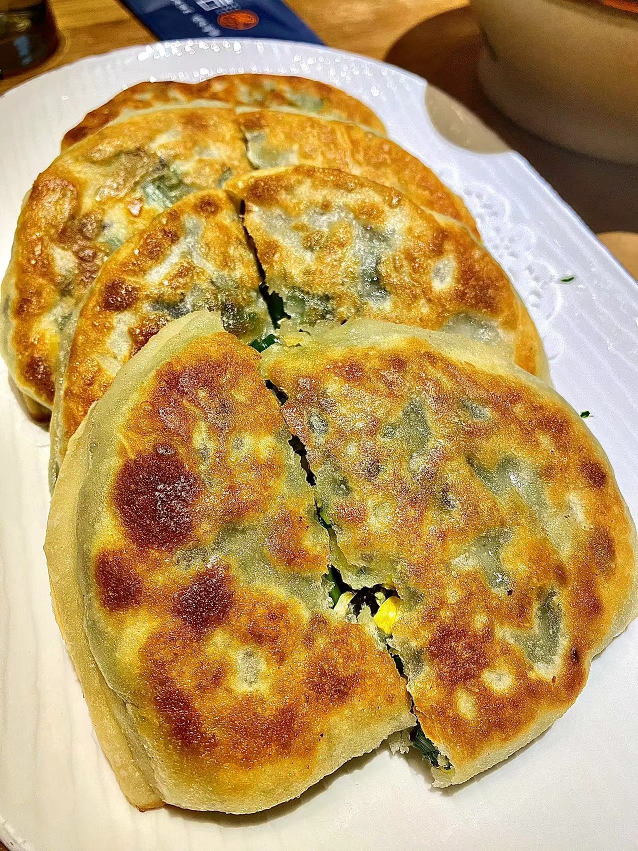 刚出锅的韭菜盒子特写，表面金黄酥脆，切开后露出翠绿馅料