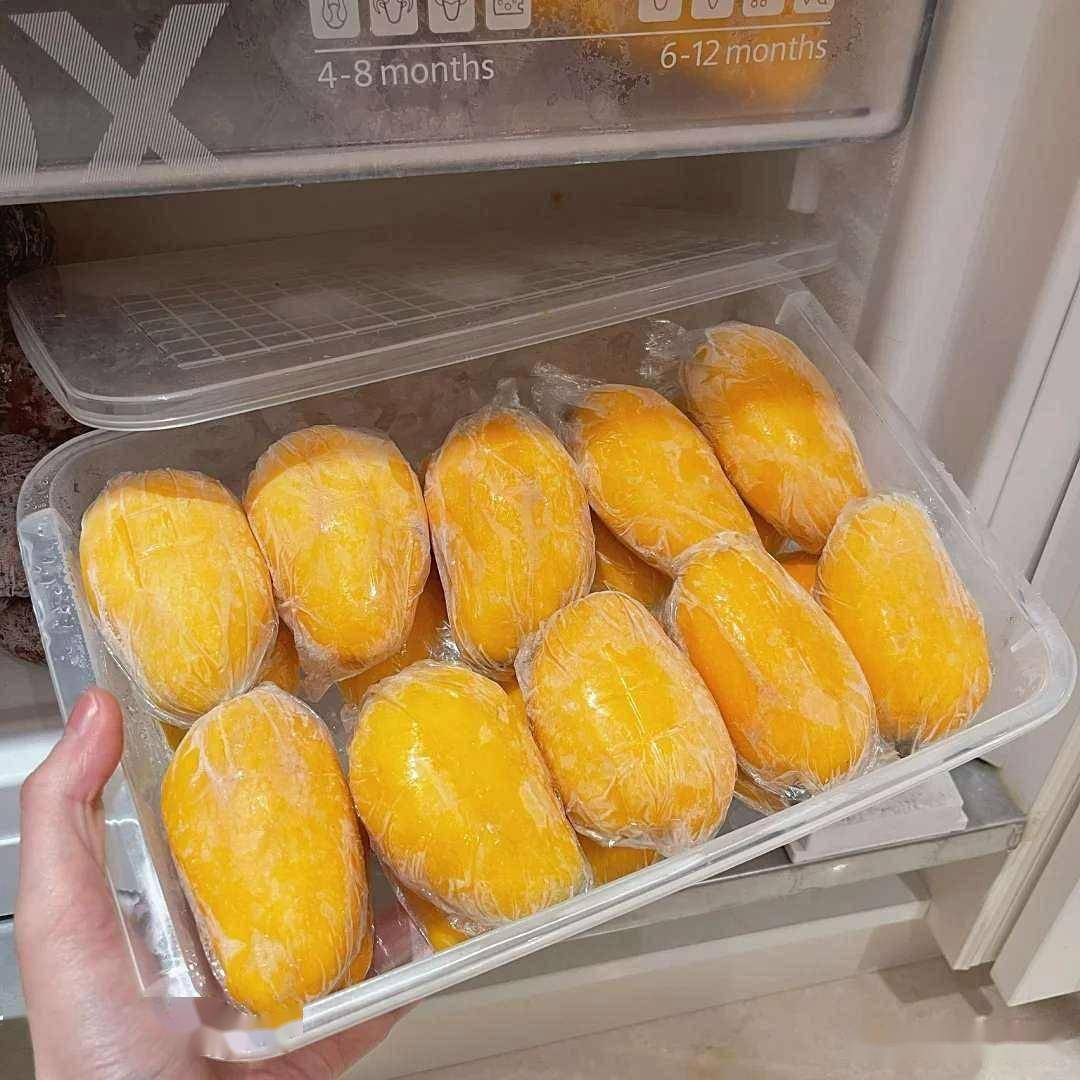 成熟的芒果被保鲜膜包裹后整齐放入透明保鲜盒，准备放进冰箱冷藏室