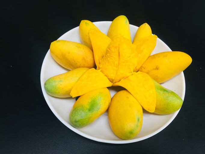 女子在厨房中用手轻捏芒果测试成熟度