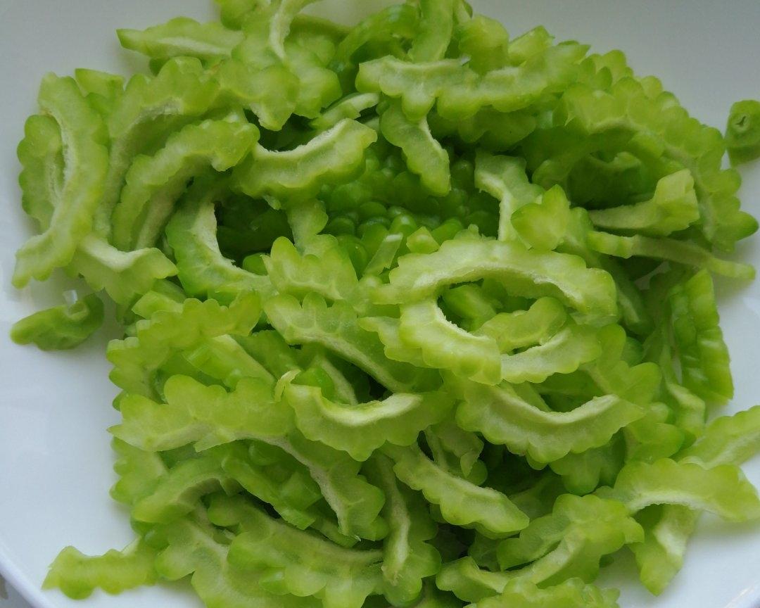 高清特写展示苦瓜柠檬冷榨汁的天然色泽与质地:苦瓜切片保留完整网状维管束结构,柠檬片透出油胞纹理,液体呈半透明翡翠色,无沉淀分层,体现未经过热处理的新鲜状态 苦瓜柠檬冷榨汁特写:青翠带籽苦瓜片与鲜黄柠檬片悬浮于澄澈淡绿色液体中,杯壁凝结细密水珠,背景为竹制砧板与不锈钢榨汁器