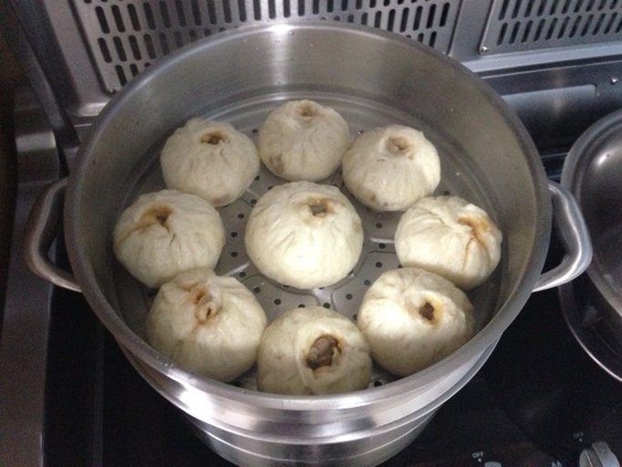 蒸锅中红皮萝卜包子正在蒸制，热气腾腾，诱人食欲