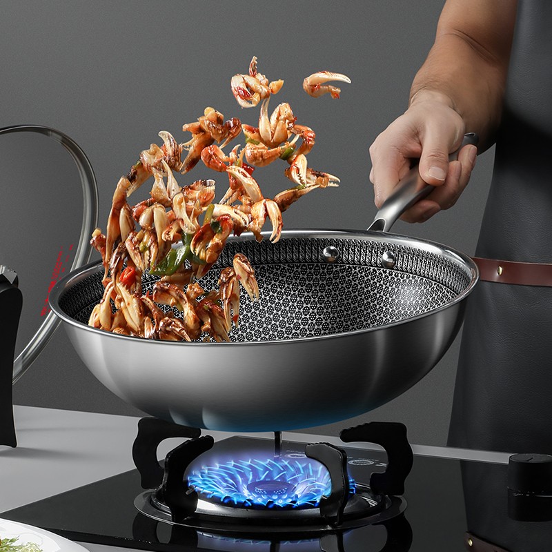 一口黑色不粘炒锅正在灶台上翻炒食材,锅内可见金黄色的土豆片与洁白的白玉菇交织在一起,蒸汽升腾,厨师手持锅铲正在颠锅,背景为现代厨房环境 烹饪过程特写