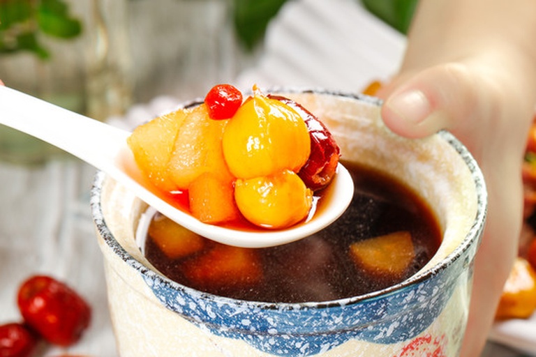 红枣桂圆糕成品图,展示一块切好的糕点,层次分明,顶部点缀枸杞,背景为传统中式餐具 红枣桂圆糕成品图